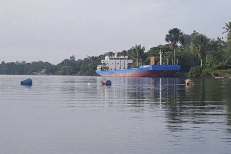 An empty barge docked on the bank of the Berbice River. Also in this photo is a line of fuel drums workers used to block river access. 