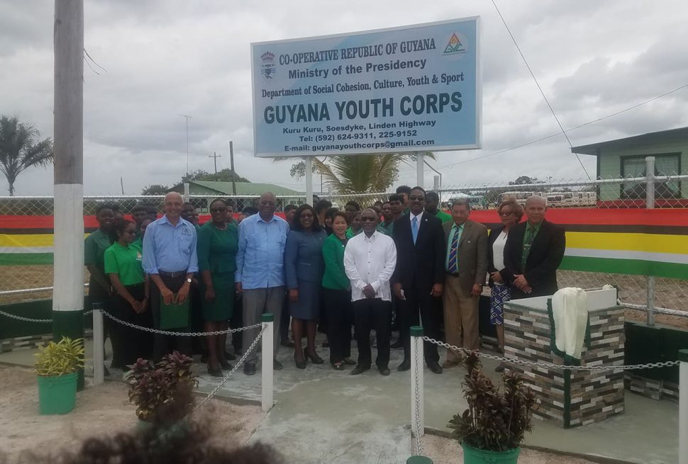 Ministers of the government and some of the students from the Guyana Youth Corps in front of the plaque and sign for the Guyana Youth Corps at the Kuru Kuru Training Centre at Soesdyke
