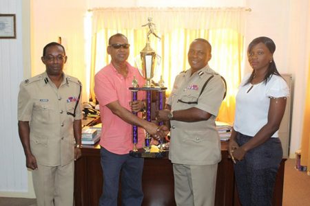 Deputy Commissioner of Police Paul Williams, receives the trophies from Trophy Stall’s Ramesh Sunich.
