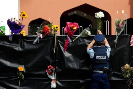 A police officer places flowers at the entrance of Masjid Al Noor mosque in Christchurch, New Zealand today. REUTERS/Jorge Silva