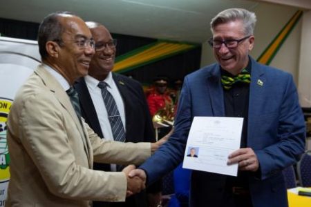Alabama-native, Pastor Harry Myers, receives the certificate confirming his Jamaican citizenship from National Security Minister Dr Horace Chang (left) during the swearing-in ceremony this morning at the Liguanea Club in New Kingston. Looking on is Andrew Wynter, CEO of the Passport, Immigration and Citizenship Agency.
