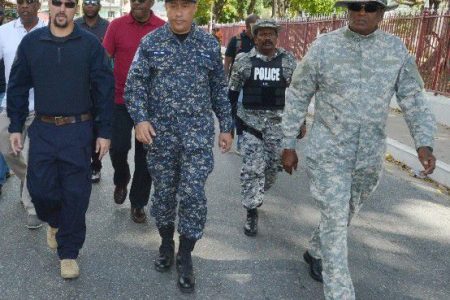 police presence: Commissioner of Police Gary Griffith, centre, in camouflage with members of the police service walks on Abercromby Street, Port of Spain on Carnival Tuesday. At left is National Security Minister Stuart Young. —Photo: ISHMAEL SALANDY