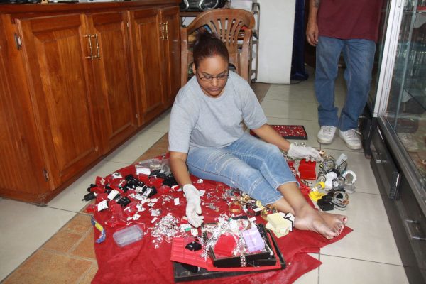 Tiana Parriag sifts through a pile of jewellery recovered by police following a heist at their Couva business place in which two robbers were shot dead, yesterday.
