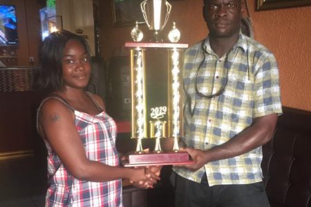 Samuel Kingston (right) receives from  Andrea Henry,  the winning trophy at Penalty Spot Sports Bar at Sixth and Albert streets Georgetown. 
