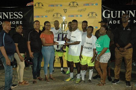 Still champs! Banks DIH Berbice representative Renesha Gilford presents the championship trophy and cash prize to Trafalgar Captain Adrian Price in the presence of Guinness Brand Manager Lee Baptiste (right), teammates and other officials following the end of the event.