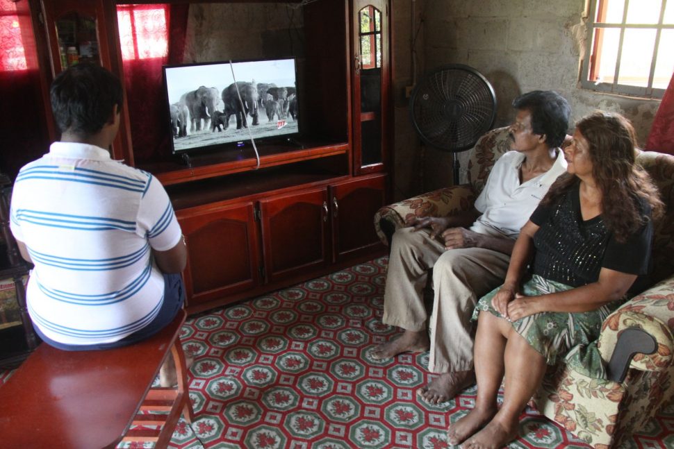Krishna Matura, his wife Balmattee and son Govinda watch their tied down television at their Hilltop Drive, Morne Roach, Gasparillo home yesterday.