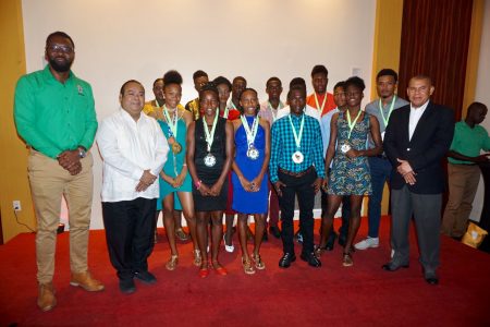  Some members of the successful Track and Field team pose for a photo with Minister of Social Cohesion with responsibility for Culture and Sport, Dr George Norton (right) and Director of Sport Christopher Jones (left) following a welcome home reception at the Pegasus Hotel last night.
