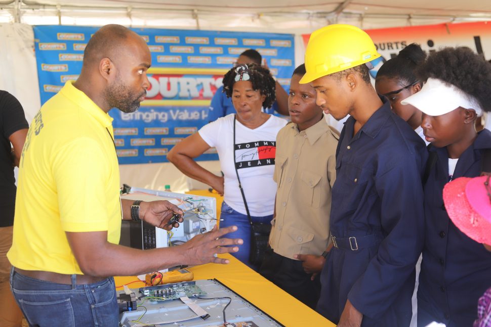 Youths paying keen attention to a demonstration given by a Courts technician at the career fair. (Terrence Thompson photo)