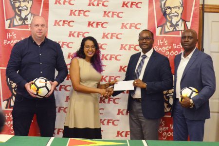 GFF President Wayne Forde (2nd from right) collecting the sponsorship cheque from Charissa Rampersaud, KFC Training Manager, during the launch of the KFC Independence Cup. Also in the photo are the GFF’s Technical Director Ian Greenwood (left) and Director of Competitions Ian Alves. (Orlando Charles photo)