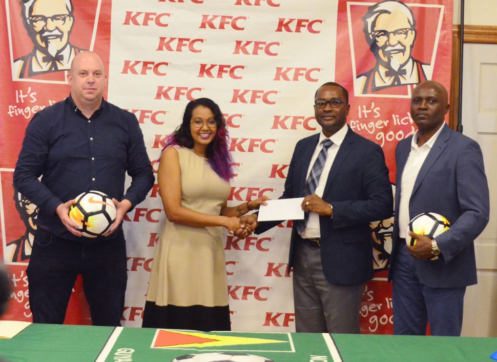 GFF President Wayne Forde (2nd from right) collecting the sponsorship cheque from Charissa Rampersaud, KFC Training Manager, during the launch of the KFC Independence Cup. Also in the photo are the GFF’s Technical Director Ian Greenwood (left) and Director of Competitions Ian Alves. (Orlando Charles photo)