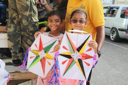 Last minute Kite Shopping: After passing the two kites back and forth between each other, these two young girls were quite happy with their decision during a last minute kite shopping outing with their dad, on Camp Street yesterday. (Terrence Thompson photo)