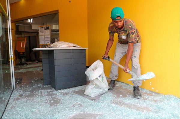 An employee shovels broken glass at a damaged branch of Banco do Brasil after a gang caused an explosion in a part of the bank in an attempted robbery, in Guararema, near Sao Paulo, Brazil April 4, 2019. REUTERS/Amanda Perobelli