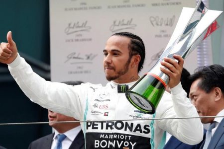 Mercedes' Lewis Hamilton celebrates winning the race on the podium with the trophy (REUTERS)