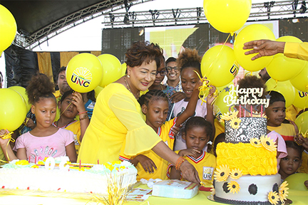 Opposition Leader Kamla Persad-Bissessar cuts her birthday and anniversary cake on Saturday children during the UNC 30th anniversary celebrations held at the Couva South Carpark.