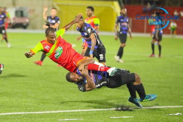 Rough Treatment-Veteran forward Gregory Richard of Fruta Conquerors being body tackled to the ground by his Jong Holland marker during the clash in the CONCACAF Caribbean Club Shield Sunday.
