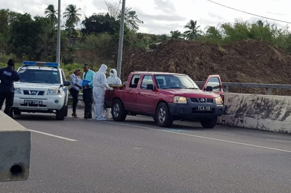 CSIs view the bodies found inside a pickup along the Solomon Hochoy Highway in St Madeleine early Monday morning.