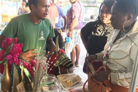 Sundried fruit producer and local farmer Andrew Campbell informing customers about his products at the Uncapped event held yesterday at the Guyana National Stadium.