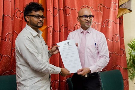 City Mayor Ubraj Narine (at left) and President of GCCI Nicholas Deygoo-Boyer display the MoU signed in the City Council Chamber yesterday. (Department of Public Information photo)