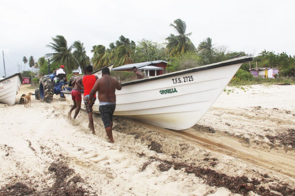 Fishermen at Icacos remove a boat from seas after a fishing trip, yesterday.