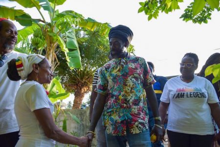 Minister of Youth Affairs, Simona Broomes (right) and Jamaican dancehall and reggae superstar Buju Banton were given a warm welcome by the members of the Rastafarian community at Victoria Village.  (Ministry of the Presidency photo)
