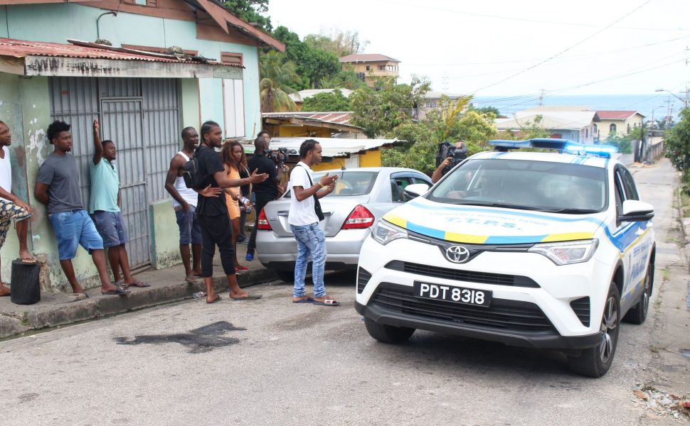 People in th Carenage area react to the presence of police officers at Big Yard yesterday, after the shootout between residents and Western Division officers on Friday night.