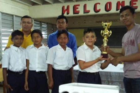 The Berbice Inter-Schools Chess Championship was hosted successfully by the Berbice Chess Association (BCA) last month. The team Championship was won by the Vryman’s Erven Secondary School. The Siparuta Primary School placed second. In photo: Vice-President of the BCA Steve Leung (left) presents a trophy to the second-place finishers. (Photo: Krishnanand Raghunandan)  
