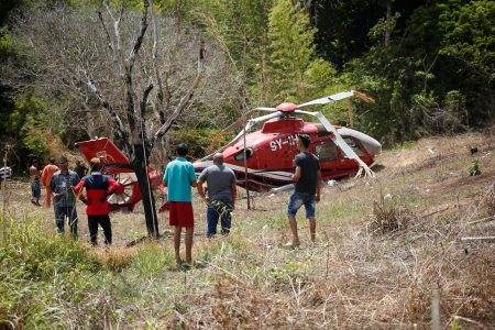 Curious onlookers survey the National Helicopter Services Limited helicopter which crashed at Windy Hill, Arouca, yesterday. The aircraft crashed while participating in the manhunt for eight escaped prisoners yesterday.