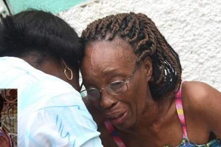 Margaret Morgan (right) is being consoled by a friend after her 15-year-old son was stabbed to death, on his way home from school, in Seaview Gardens, St Andrew yesterday. (Photo: Garfield Robinson) 