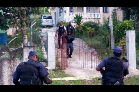 Police officers outside the gate of the house in Comfort, St James, where a man was shot after stabbing his eight-year-old son early Tuesday morning.
