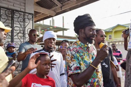 Buju Banton enjoying a mango as he interacted on Sunday with the youths of Leopold Street, Georgetown. (Ministry of the Presidency photo)