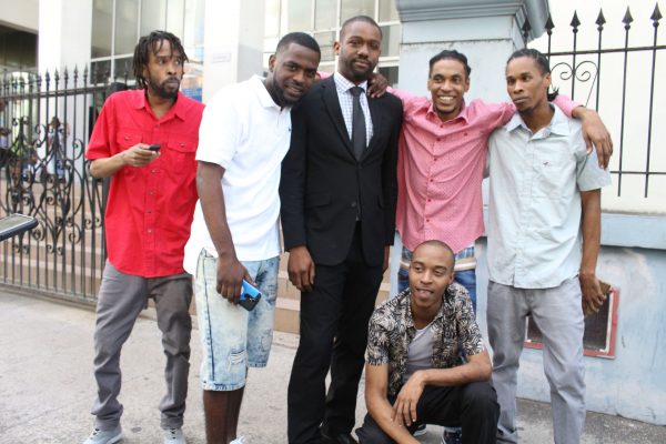 Attorney CJ Williams, centre, with his clients, from left, Akili Charles, Chicki Portillo, Isreal Lara, Levi Joseph and Kareem Gomez stand outside the Port-of-Spain Magistrates Court after they were freed, yesterday.