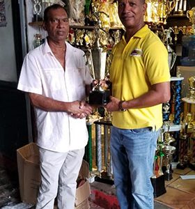Proprietor of Trophy Stall, Ramesh Sunich (left) hands over a trophy to AAG President Aubrey Hutson yesterday. 
