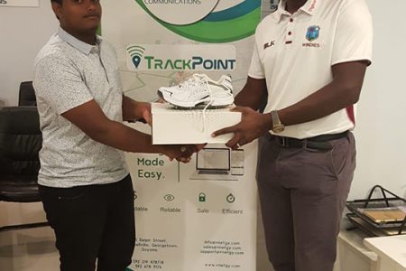 Amit Persaud (left) receives his first pair of spike boots from Essequibo Coach, Ryan Hercules on behalf of V-Net Communications