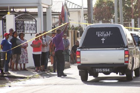 A crowd looks on as members of the Singh family who died in a fire at their Samaroo Street, Aranguez, home yesterday, are taken away by undertakers.