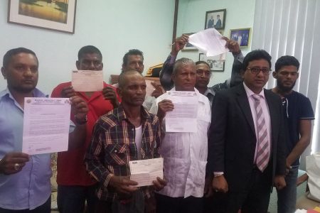 The seven farmers holding their documents. They are accompanied by attorney Anil Nandlall (second from right).