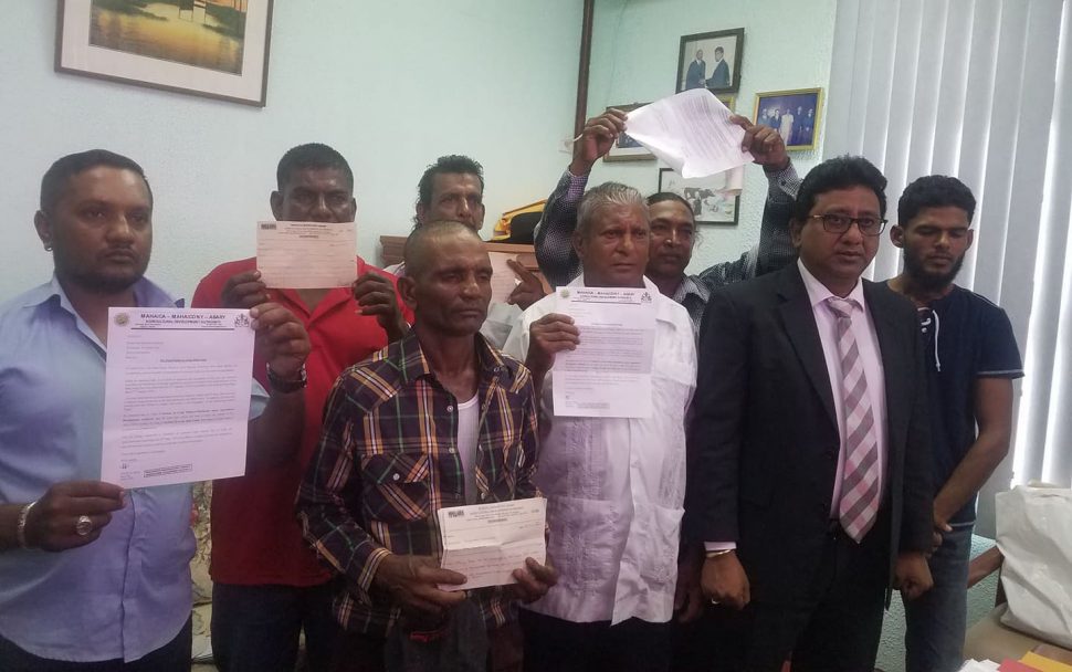 The seven farmers holding their documents. They are accompanied by attorney Anil Nandlall (second from right).