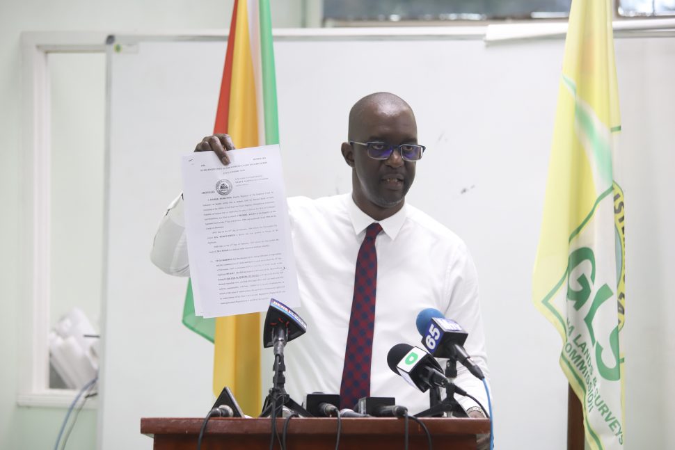 Head of the Guyana Lands and Surveys Commission Trevor Benn displays for reporters a court order, dated 1996, which he claimed the former administration failed to honour and which has since returned more than 2,000 acres of state lands to Muriel Allen. (Photo by Terrence Thompson) 