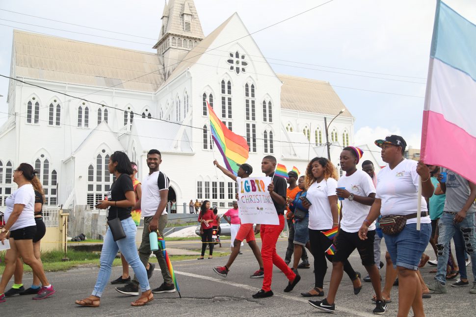 Pride Parade revellers waving their rainbow flags as they pass St George’s Cathedral while on their way to the Square of the Revolution yesterday. (Terrence Thompson photo)
