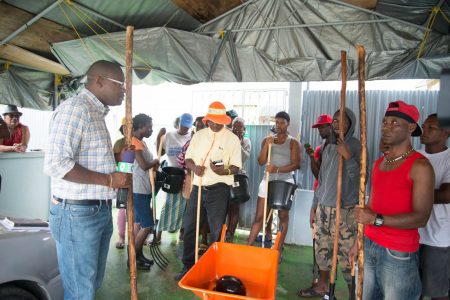 Minister of Public Infrastructure David Patterson (at left) speaking with Sophia residents yesterday when he handed over several wheelbarrows, shovels, forks and other tools to be used for cleaning the community’s drains. (Department of Public Infrastructure photo)