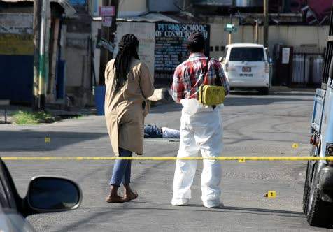 Homicide investigators at the scene where two people were shot dead in Spanish Town, yesterday. (Photo: Naphtali Junior) 