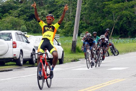 Jamaul John celebrates after he out sprinted Andrew Hicks and last year’s champion, Curtis Dey at the end of an aggressive day of racing from the city to Moblissa on the Linden Highway and back. (Orlando Charles photo)