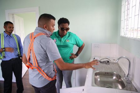 A flaw in one of the houses being pointed out to Minister within the Ministry of Communities, with responsibility for Housing, Annette Ferguson (right). (DPI photo) 