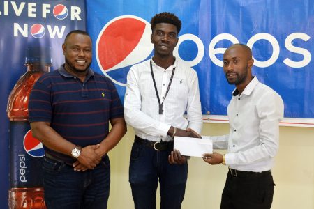 Pepsi Brand Manager Larry Wills [right] making the presentation to Petra Organization representative Mark Alleyne [centre] while Petra Director Troy Mendonca looks on.
