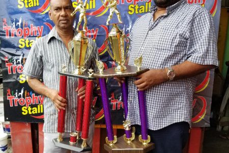 Trophy Stall’s CEO, Ramesh Sunich, left, hands over trophies to Hilbert Foster.