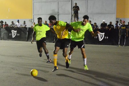Ryan Dowding (in yellow) of Broad Street trying to maintain possession of the ball while being
challenged by a John Street player at the Berlin Tarmac during the Guinness ‘Greatest of the Streets’ Georgetown Championship last evening. (Orlando Charles photo)