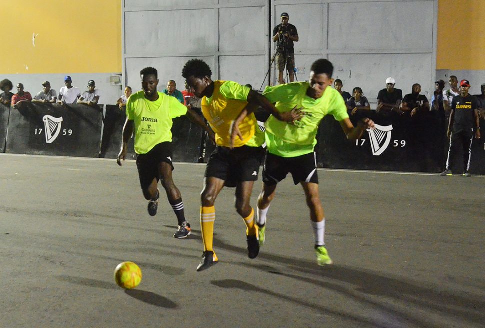 Ryan Dowding (in yellow) of Broad Street trying to maintain possession of the ball while being 
challenged by a John Street player at the Berlin Tarmac during the Guinness ‘Greatest of the Streets’ Georgetown Championship last evening. (Orlando Charles photo)