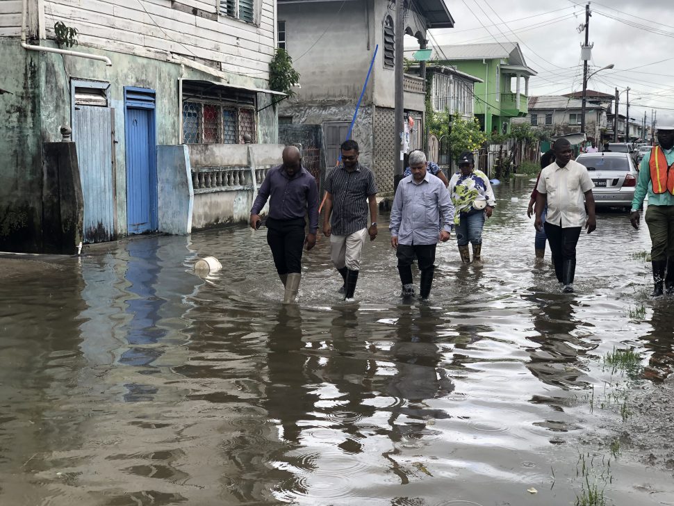 Mayor Ubraj Narine (centre), along with Minister within the Ministry of Public Infrastructure, Jaipaul Sharma (right), wading through the floodwater in Albouystown yesterday morning
