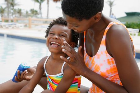 A mother applies sun cream to her child in an effort to protect her skin from the sun. (https://www.consumerreports.org photo)