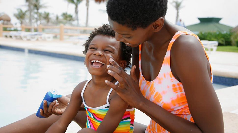 A mother applies sun cream to her child in an effort to protect her skin from the sun. (https://www.consumerreports.org photo)