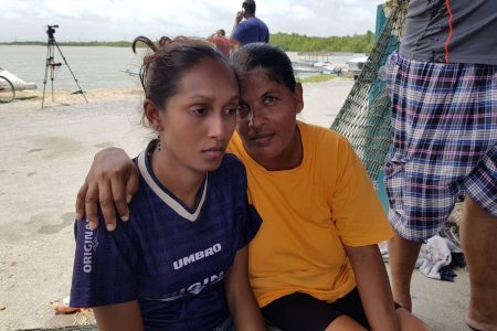 Relatives of the missing fishermen Sahidan Khan left,  wife of Anand Rampersad and Nazeema Ramdeo, mother of Shiva Ramdeo, right, console each other at the Orange Valley Fishing Depot yesterday. 